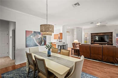 Dining room featuring ornamental molding, a ceiling fan, wood finished floors, and a chandelier