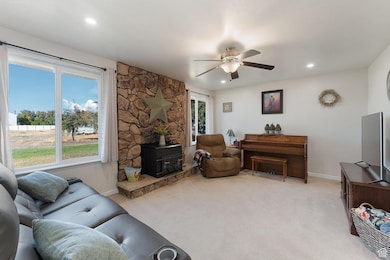 Living area featuring a wood stove, light carpet, recessed lighting, and ceiling fan