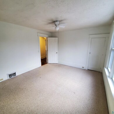 Empty room featuring ceiling fan, light colored ca