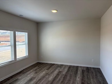 Empty room with dark wood-style flooring and recessed lighting