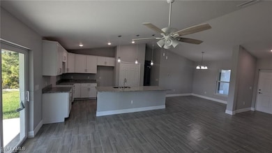 Kitchen with baseboards, lofted ceiling, a sink, a