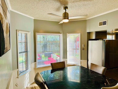 Dining room featuring crown molding, a textured ceiling, and a ceiling fan