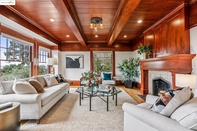 Living area with a fireplace, light wood-style floors, a wooden ceiling with exposed beams, and recessed lighting