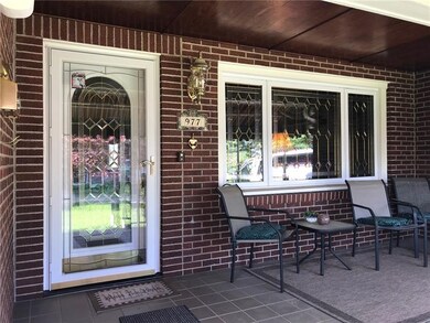 Covered front porch with tile floor and leaded gla
