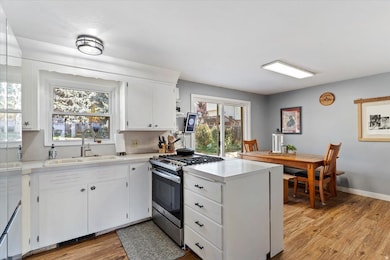 Kitchen featuring gas range, light countertops, a peninsula, white cabinets, and laminate floors