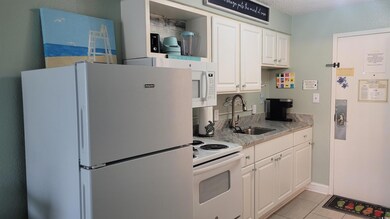 Kitchen featuring white appliances, white cabinetry, and light tile patterned floors