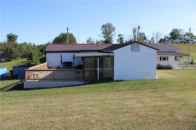 Rear view of house with a lawn, a wooden deck, and a metal roof