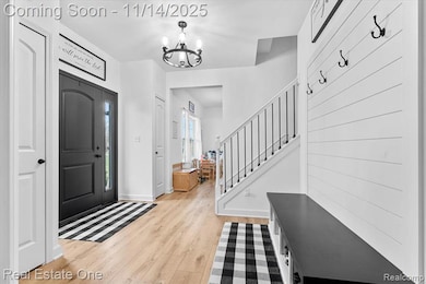 Entryway with light wood-type flooring, stairway, and a chandelier