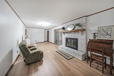 Living area featuring ornamental molding, a brick fireplace, and light wood finished floors