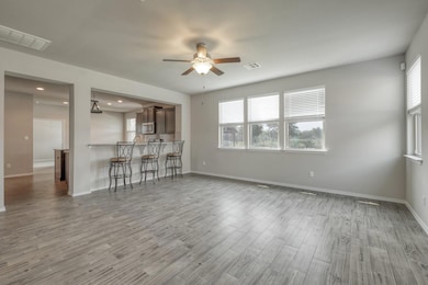 Unfurnished living room with ceiling fan, wood fi