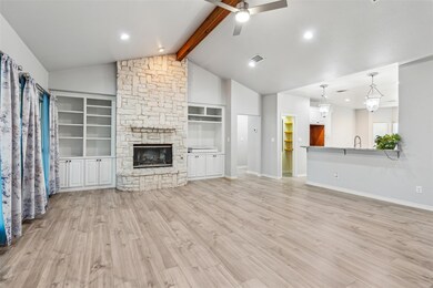Unfurnished living room featuring beamed ceiling, ceiling fan, a stone fireplace, and light hardwood / wood-style flooring