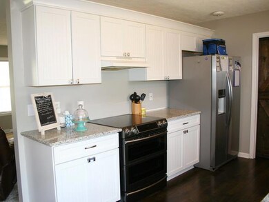 Lovey white cabinets,granite,glass top stove and stainless refrigerator.