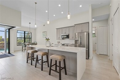 Kitchen with light hardwood / wood-style floors, pendant lighting, a spacious island, a breakfast bar, and appliances with stainless steel finishes
