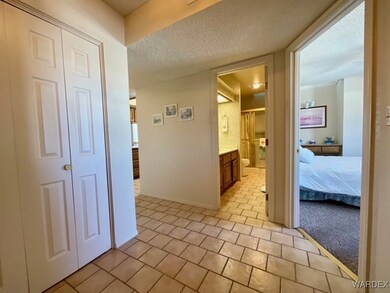 Corridor with a textured ceiling, baseboards, and