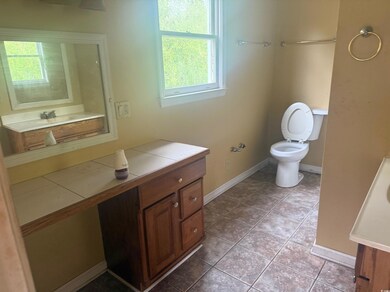 Bathroom with baseboards, toilet, vanity, and tile