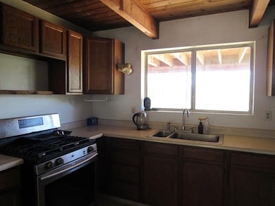 Kitchen with wood ceiling, beam ceiling, stainless steel gas range, and sink