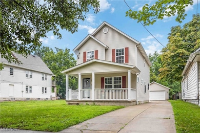 View of front of house with a porch, an outdoor structure, a front lawn, and a garage
