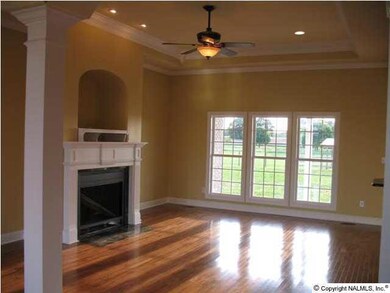 Spacious family room with glossy hardwoods, gas log fireplace & wall of windows overlooking covered back porch.