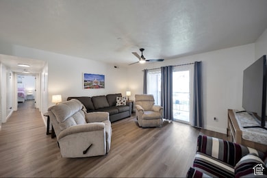 Living room with wood finished floors, ceiling fan, and a textured ceiling