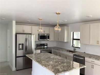 Kitchen with stainless steel appliances, a sink, light stone counters, a center island, and pendant lighting