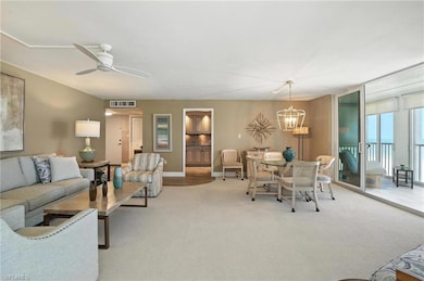 Living area featuring carpet floors, a chandelier, and ceiling fan - Virtually Edited Image