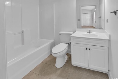 Full bathroom with toilet, tile patterned floors, 