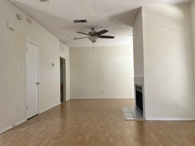 Unfurnished living room featuring a textured ceiling, a tile fireplace, light wood-style flooring, and ceiling fan