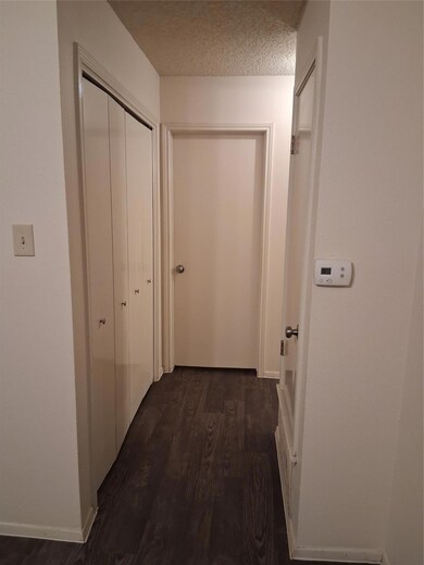 Hall featuring dark wood-style flooring and a textured ceiling