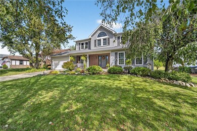 Traditional-style house featuring covered porch, a front yard, driveway, and an attached garage