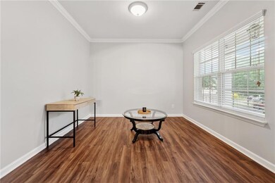 Sitting room with ornamental molding, wood finished floors, and baseboards