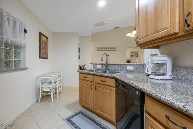 Kitchen featuring black dishwasher, light tile patterned floors, light stone counters, and brown cabinets