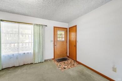Entryway with wood doors, large picture window, and carpet flooring. - 5292 Java Rd, Java, VA 24565