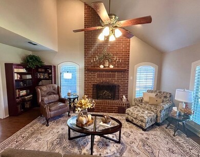 Living area featuring a fireplace, high vaulted ceiling, wood finished floors, and ceiling fan