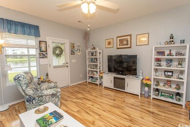 Living room featuring light wood-type flooring, a water view, and a ceiling fan