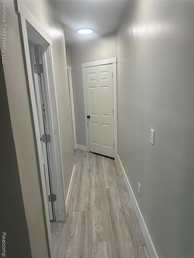 Hallway with light wood-style flooring and baseboards