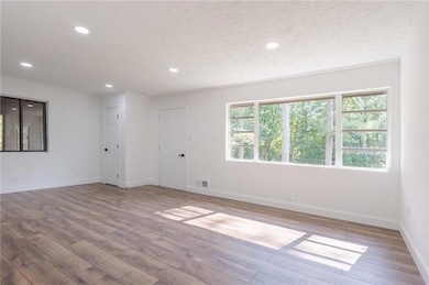 Unfurnished room with light wood-style floors, recessed lighting, a textured ceiling, and baseboards