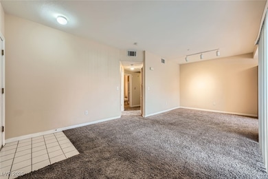 Carpeted empty room with track lighting, tile patt