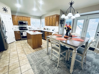 Kitchen with brown cabinetry, light countertops, a center island, decorative backsplash, and light tile patterned flooring