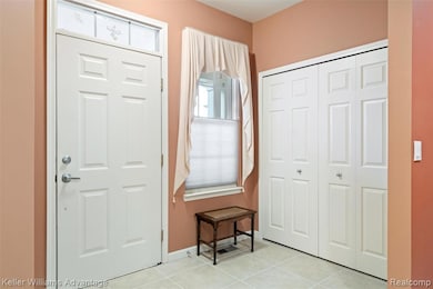 Foyer entrance with light tile patterned floors and baseboards