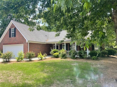 Ranch-style home with brick siding, a front lawn, a shingled roof, and a porch