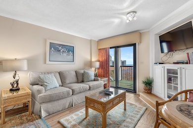 Living area featuring light wood-type flooring, a textured ceiling, and ornamental molding