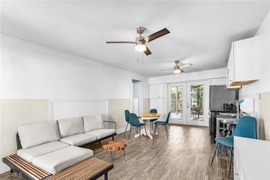Living room featuring light wood finished floors, a ceiling fan, and french doors