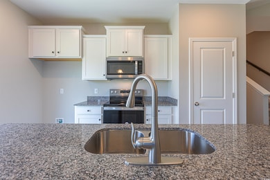 Kitchen featuring dark stone countertops, white ca