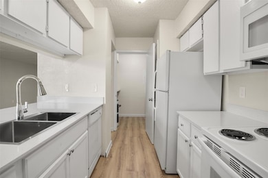 Kitchen featuring sink, white cabinetry, a texture