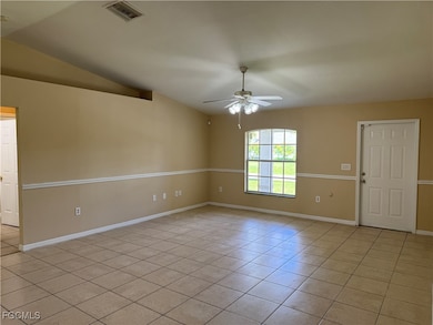Empty room featuring light tile patterned floors, vaulted ceiling, and ceiling fan