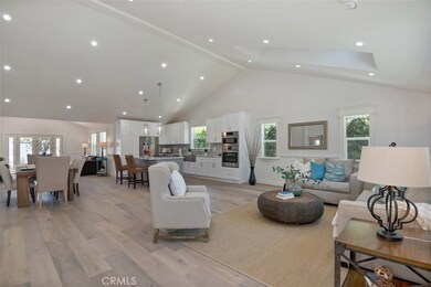 Open Concept Living room featuring vaulted ceilings and recessed lighting, wainscoting and craftsman detail on the window trim.