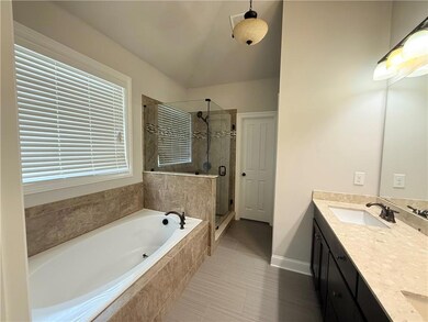 Full bath featuring a garden tub, a shower stall, double vanity, and tile patterned floors