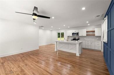 Kitchen featuring appliances with stainless steel finishes, open shelves, a kitchen bar, recessed lighting, and open floor plan
