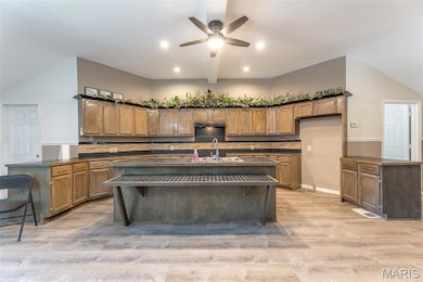 Kitchen with dark countertops, ceiling fan, recessed lighting, brown cabinetry, and light wood-type flooring
