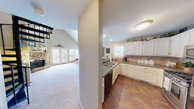 Kitchen with a sink, white cabinets, light stone counters, and stainless steel appliances